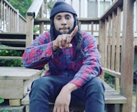 a man with dreadlocks sitting on a wooden bench