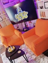 a living room with two orange chairs and a tv