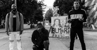 black and white photo of a group of men standing on a sidewalk