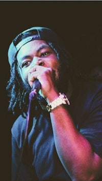 a man with dreadlocks singing into a microphone