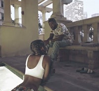 a man and woman sitting on a ledge next to a pool