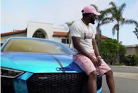 a man sitting on top of a blue audi sports car